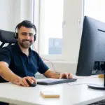 Sympathischer Aurenus-Mitarbeiter mit Headset am ergonomischen PC-Arbeitsplatz in Zug.