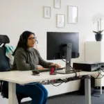 Fokussierte Aurenus Telemarketing-Mitarbeiterin im Kundengeschaeft am ergonomischen Tisch.