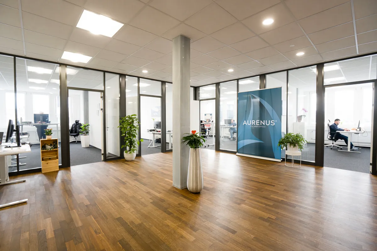 Einladender Empfangsbereich mit modernem Parkett und Glasfronten am Hauptsitz in Steinhausen.