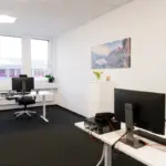 Ruhiges Zweier-Buero mit ergonomischen Bildschirmarbeitsplaetzen und moderner Einrichtung.