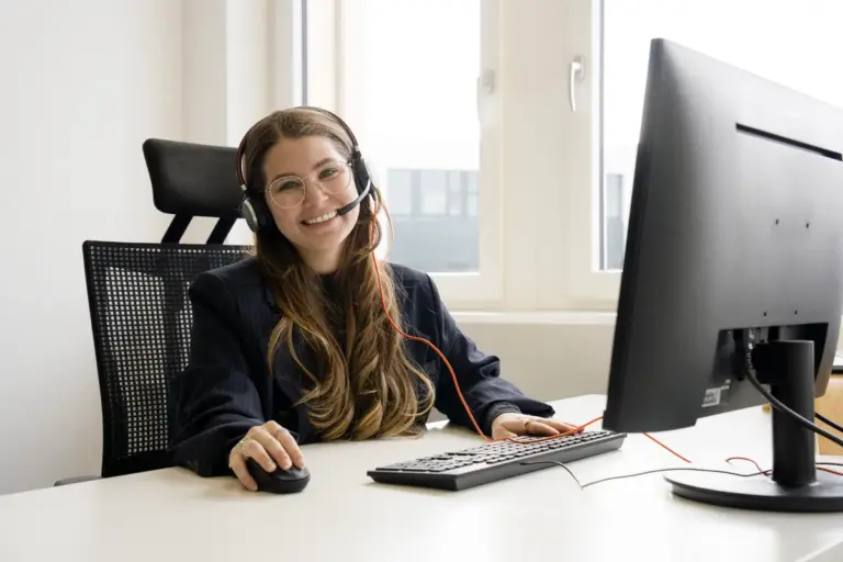 Erika lächelt mit Kopfhörern beim Telefonieren im Callcenter für professionelles B2B- und B2C-Telemarketing der Aurenus AG in der Schweiz.